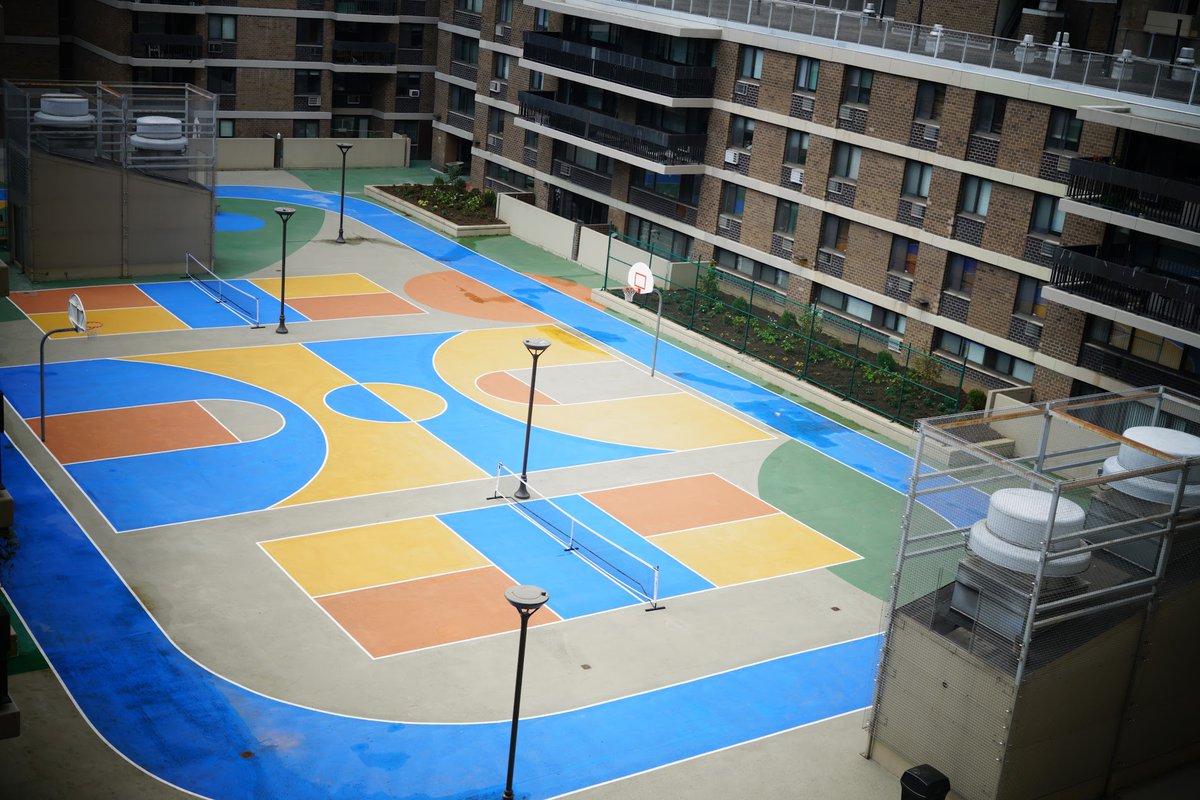 Aerial view of the private sports court, painted in bright primary colors, with basketball and pickleball lines