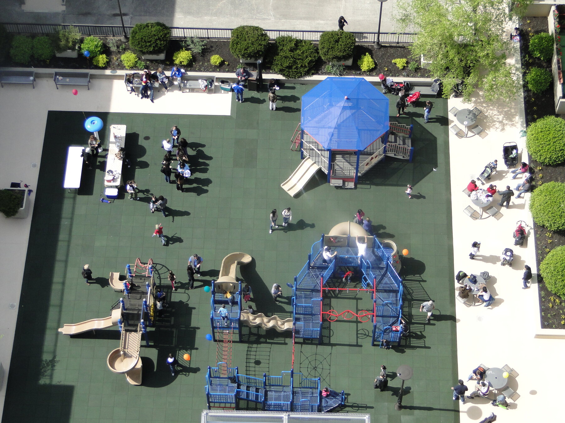 Aerial view of the Southbridge Towers playground in active use, with families on the climbing structures and shaded play area