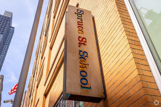The Spruce Street School (PS 397) signboard mounted on the building, with the Frank Gehry tower rising behind
